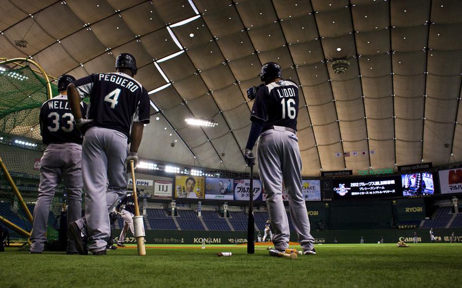 Seattle Mariners players Casper Wells, Carlos Peguero and Alex Liddi wait to bat during practice Saturday at the Tokyo Dome in Tokyo.