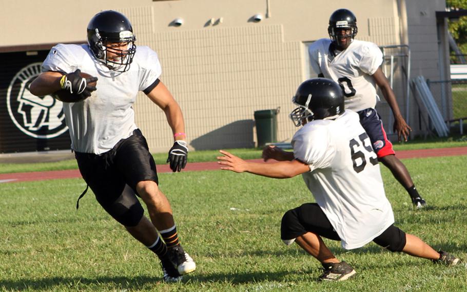 Ballcarrier Andre Encarnacion eludes defender Keiyl Sasano as David Coleman watches during Zama American High School's football practice Aug. 14, 2012.