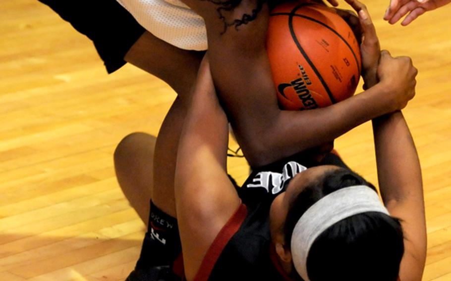Area I guard Zori Drew and Camp Humphreys guard Jamie Jones scrum for the ball during Saturday's women's championship game in the 27th Osan Defenders Pacificwide Holiday Basketball Tournament at main fitness center, Osan Air Base, South Korea. The Bulldogs beat the Warriors 68-61.