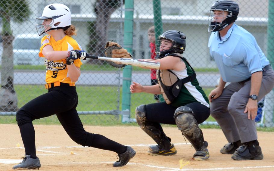 Kadena Panthers outfielder Morgan Beecher follows through on her swing as Kubasaki Dragons catcher Kaite Farley and home-plate umpire Roy Paul watch during the Okinawa Activities Council high school girls softball game April 30, 2013, at Camp Foster, Okinawa. Kadena won 14-4 in five innings in a game shortened by the 10-run rule.