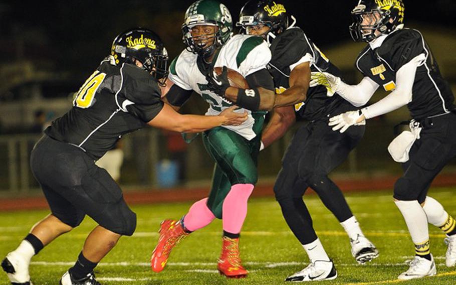 Kadena defenders Gage Bongo, Preston Harris and Justin Sego surround Kubasaki running back Jarrett Mitchell during Friday's football game at Kadena Air Base, Okinawa. Kadena won 11-0, capturing its first island season series since 2010.