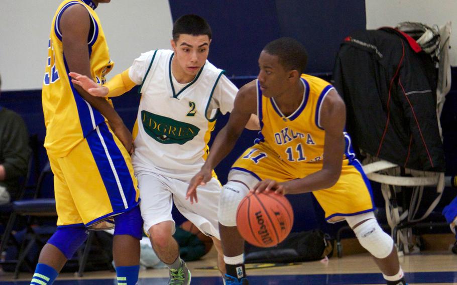 Yokota guard J.J. Henderson looks to drive around the pick set by teammate Marcus Henagan as Robert D. Edgren's Izzy Leon defends during Friday's DODDS Japan boys high school basketball game at Misawa Air Base, Japan. Yokota won 70-37.