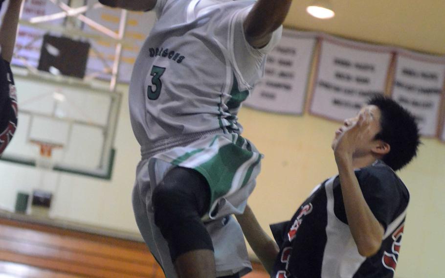 Kubasaki guard DeQuan Alderman goes up between Ginowan defenders for a shot during Friday's high school basketball game at Camp Foster, Okinawa. The Dragons beat the Redhawks 97-83.