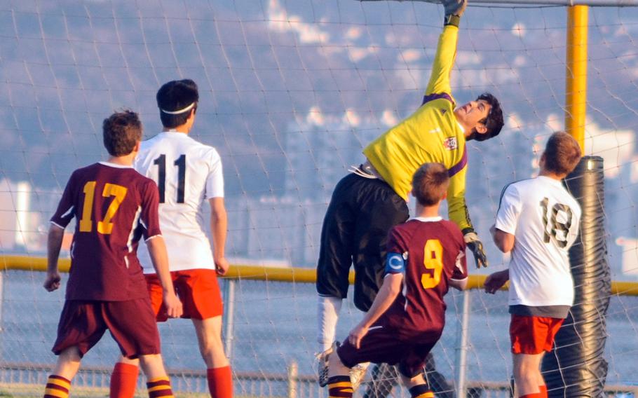 Nile C. Kinnick goalkeeper Brady Yoder leaps for the ball flying over the net in front of teammates Branden Yoder and Matthew C. Perry's Sam Hess and Aidan Lewis during Friday's DODDS Japan high school boys soccer match at Yokosuka Naval Base, Japan. The Red Devils won 3-1.