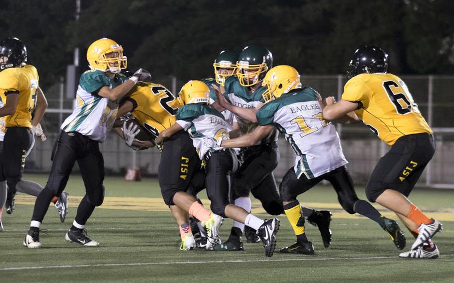 ASIJ running back Zach Noddin drags the Robert D. Edgren defense for a few extra yards during the Mustangs' 2014 season opener Friday, Sept. 5 in Chofu, Japan. ASIJ would go on to win 39-0.