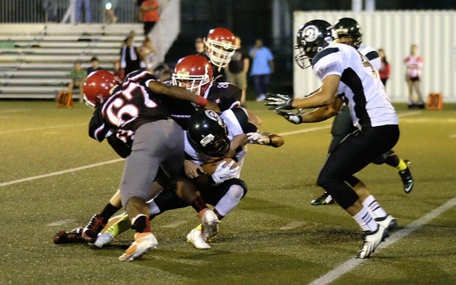 Kubasaki running back Jacob Green is hit in the backfield by Nile C. Kinnick defensive linemen Dwayne Lyon and Dustin Thompson in the Dragons 22-18 season opening loss to the Red Devils at Fleet Activities Yokosuka on Sept. 13.