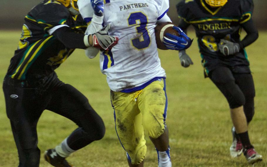 Yokota running back Decorio Perry, who set the tone with a 63-yard touchdown run on the game's third play, eludes the tackles of Edgren's Joshua Bibbee and Roman Perez on Friday at Misawa Air Base, Japan.
