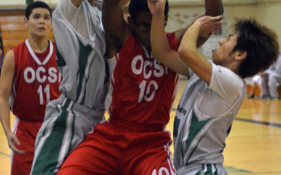 Kubasaki's Imani Washington and Eiji Graves sandwich Okinawa Christian International's Freddie Hatch in a battle for a rebound during Thursday's Okinawa boys high school basketball season-opening game for both teams. The host Dragons beat the Crusaders 78-39.