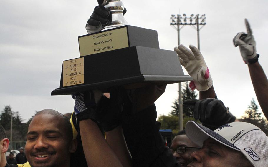 Players and coaches celebrate with the trophy after Army shut out Navy 20-0 at Camp Zama on Saturday.