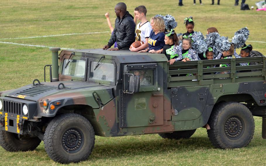 A Humvee, with the game ball in tow, makes its way onto the field before the game. Holding the ball is 10th Regional Support Command's youngest soldier, Pvt. Cody McTaggard; he's flanked by CFAO Sailor of the Year Petty Officer 2nd Class Brenetton Kinchenbirtwum and Naval Hospital Okinawa Sailor of the Year Petty Officer 1st Class Sondra Zickmund.