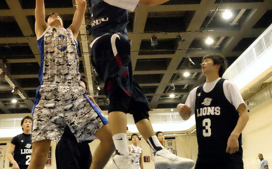 Avi Schaefer of St. Mary's International skies past Nittai University freshman team players for a rebound during Saturday's round-robin play in the 5th Fred Sava Memorial Basketball Tournament at St. Mary's International School, Tokyo. The Titans outlasted the Lions 80-68 in overtime.