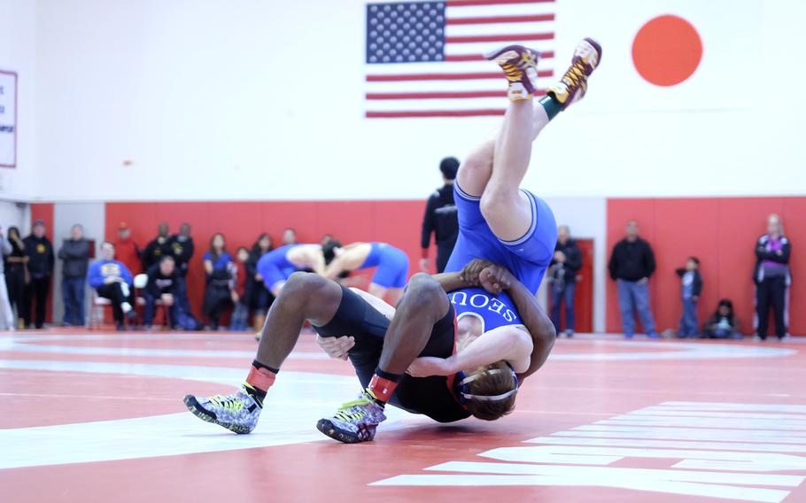 Nile C. Kinnick's Dre Paylor, left, throws Seoul American's Tristan Johnson in the second round of the Beast of the East 168-pound weight class.