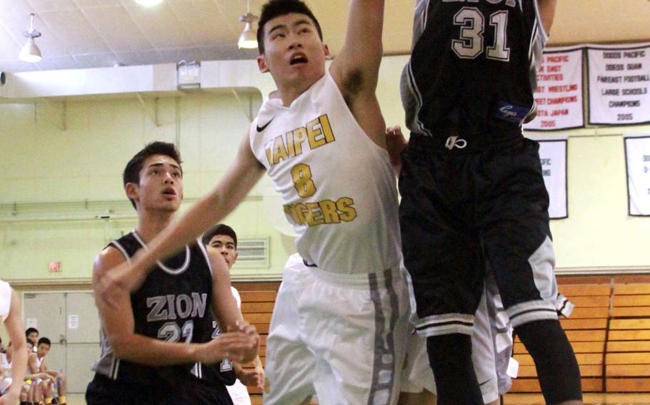 Zion Christian's Rejay Maruo skies for a rebound against Taipei American's Jon Chen as Lions teammate D.J. Anthes watches during Sunday's basketball game. The Tigers beat the Lions 76-73.