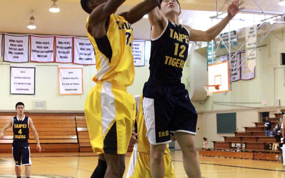 Kadena's Boysie Gordon and Taipei American's Riley Chang go up for a rebound during Sunday's basketball game. The Panthers beat the Tigers 80-68.