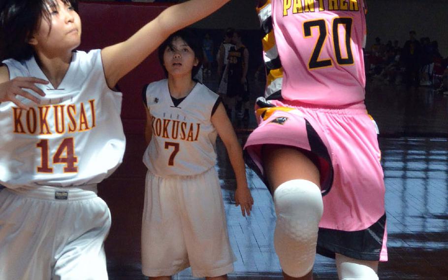 Kadena's Brenda Gulley drives to the basket against Naha Kokusai's Saaya Takara during Saturday's pool-play game in the 9th Okinawa-American Friendship Basketball Tournament, Jan. 24, 2015. Kadena won 41-39.