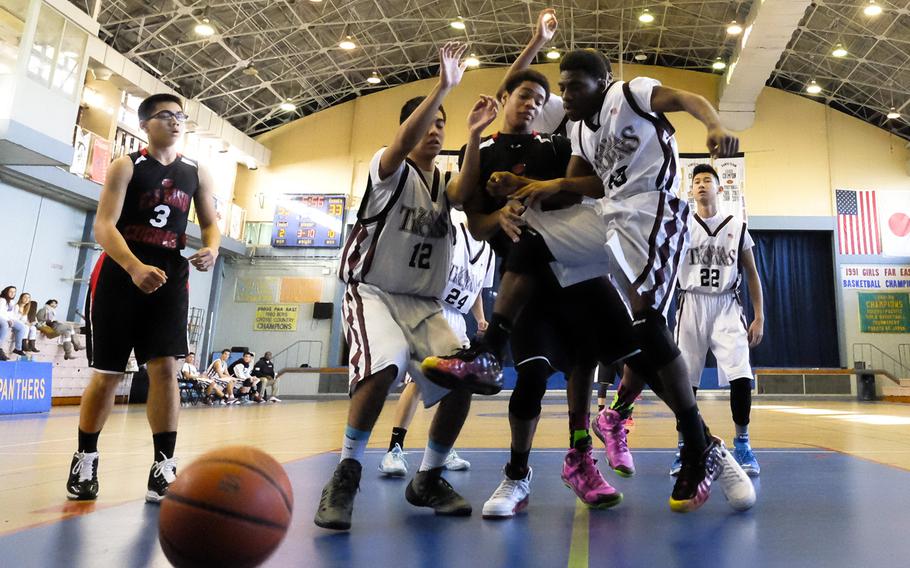 E.J. Kng's Dijon Johnson is fouled hard by several Zama defenders while attempting a shot during bracket play of the DODDS Japan Basketball Tournament on Friday at Yokota Air Base, Japan. King would lose the game 64-43.