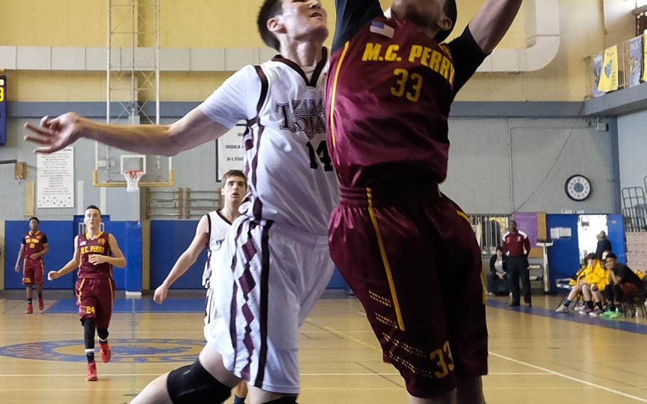 Zama's Joseph Atkinson blocks a shot attempt by M.C. Perry's Tyson Moore during the third-place game of the DODDS Japan Basketball Tournament on Saturday at Yokota Air Base, Japan. Perry would defeat its rival 55-52.