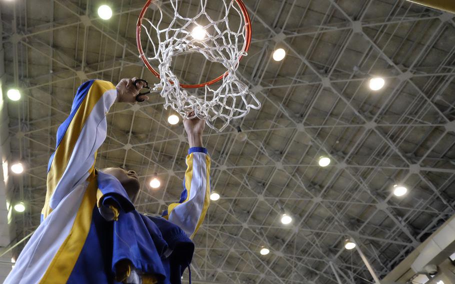 Yokota's Marcus Henagan cuts down the net following  the DODDS Japan Basketball Tournament championship Saturday at Yokota Air Base, Japan. Henagan's team defeated Robert D. Edgren 84-53.