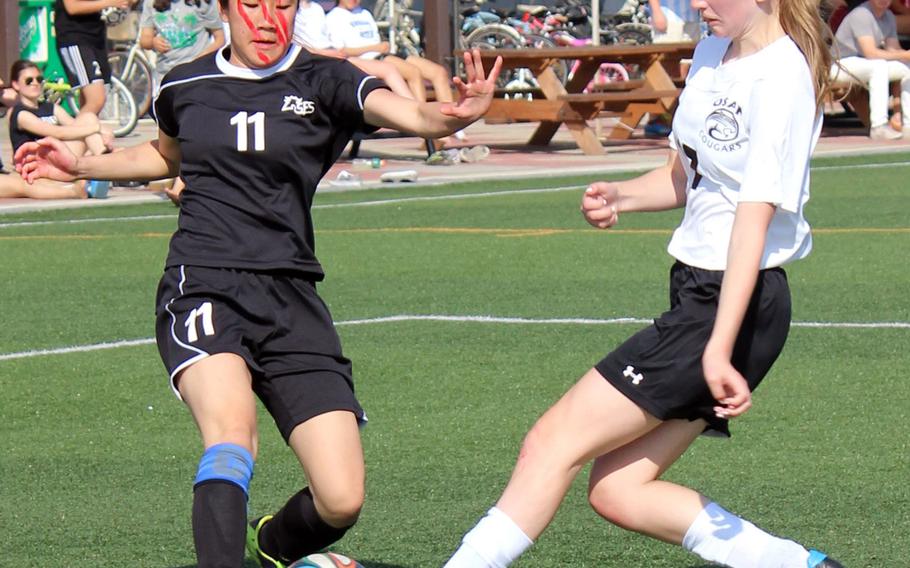 Seoul Foreign's Sasi Banyatpiyaphod and Osan American's Hannah Cleveland make a play for the ball April 25, 2015, during the Korea girls soccer tournament final, won by the Crusaders 4-2 over the regular-season champion Cougars. Banyatpiyaphod was named tournament MVP.