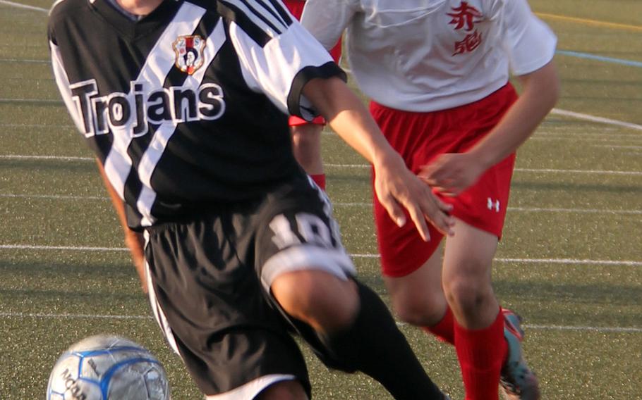 Zama's Logan Perera dribbles in front of Nile C. Kinnick's Bryan Wolf and Brady Yoder during Thursday's boys soccer match, won by the Trojans 3-2.