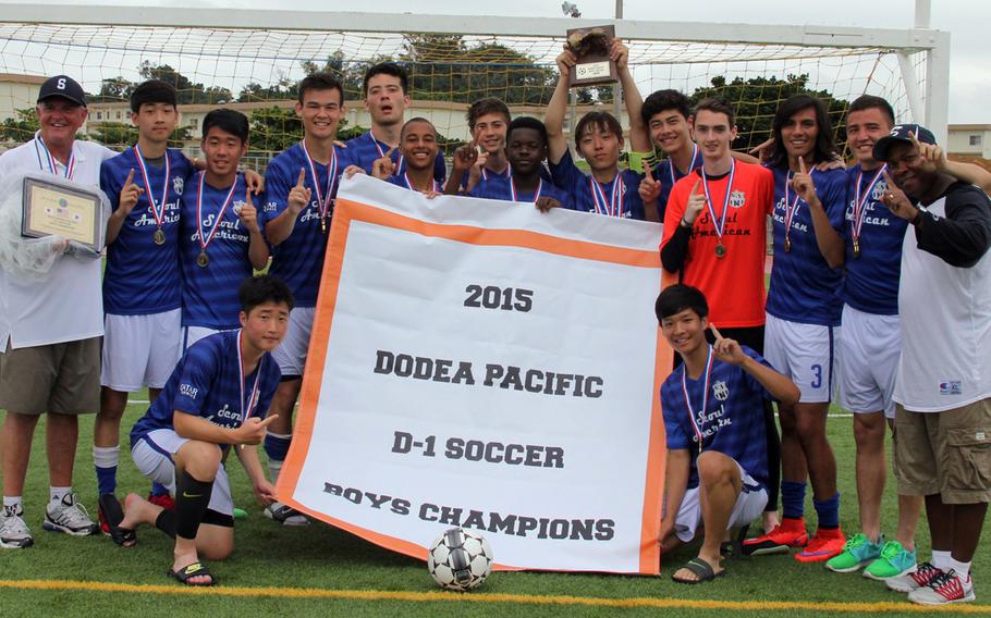 Banner time for the Falcons. Seoul American's boys soccer team gathers around the banner and displays the championship hardware.