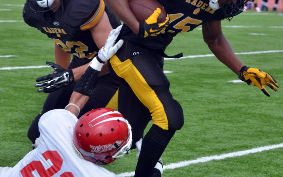 Kadena running back Jason Bland tries to slither out of the tackle of Nile C. Kinnick's Nick Galegher.