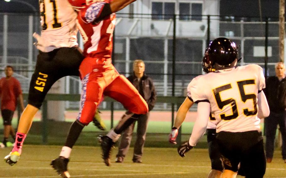 American School In Japan's Andrew Meaney and Nile C. Kinnick's Devoney Stanley go up for a pass.