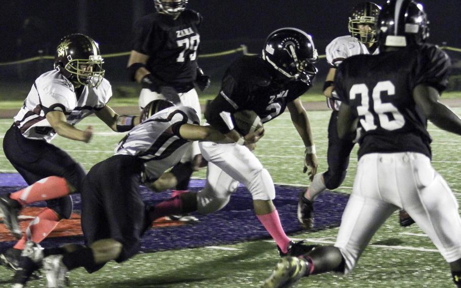 Zama running back Keiyl Sasano drags Matthew C. Perry defender Desmond Moore as he fights for yardage.