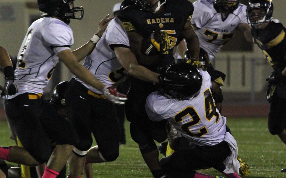 Kadena running back Jason Bland gets wrapped up by a herd of ASIJ Mustangs.