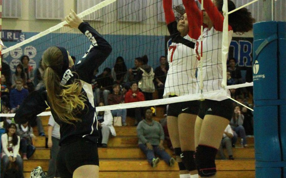 Seoul American's Jessica Gardner goes up to hit the ball against the block of Nile C. Kinnick's Keisha Hadorn and Aya Stewart during Monday's round-robin play in the Far East Division I volleyball tournament. The Red Devils swept the host Falcons 25-14, 25-22.