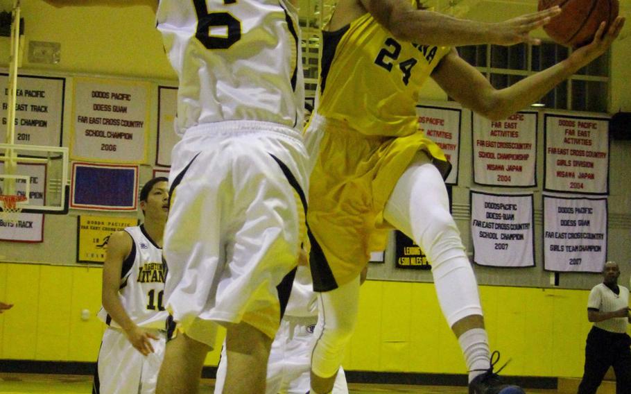 Kadena's Justin Wilson skies for the hoop against Kitanakagusuku's Kainalu Motes during Friday's high school boys basketball game. The host Panthers fell 91-87 to the Fighting Lions.