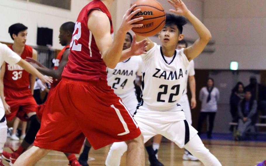 Nile C. Kinnick's Josiah Furgeson looks to pass as Zama's Shin-ya Hamada defends during Tuesday's boys basketball game, won by the Red Devils 58-28.