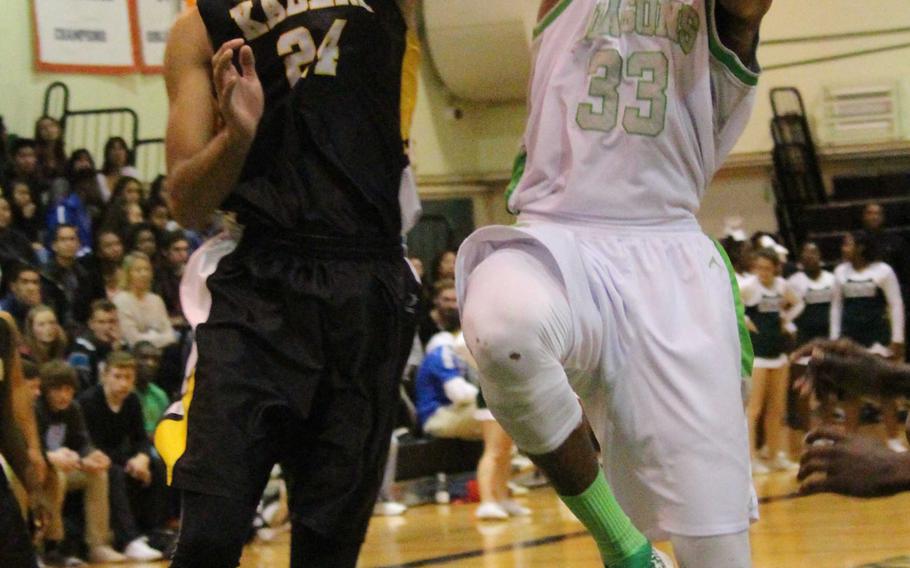 Kubasaki's Matt Ashley takes it to the hoop against Kadena's Justin Wilson during Friday's boys basketball game, won by the Dragons 67-49. They completed a sweep of the regular season against the Panthers.