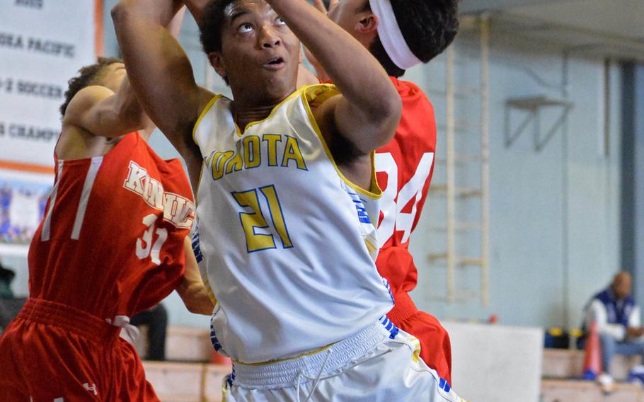 Yokota's Jam Harvey tries to recover the ball against Kinnick's Davion Roberts and Xavier Torres during Saturday's DODDS Japan boys final, won by the Panthers 62-52.
