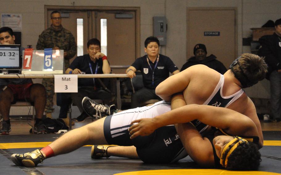 Seoul American's Connor Knight puts the hurt on Kadena's Siu Fuimaono in the heavyweight match.