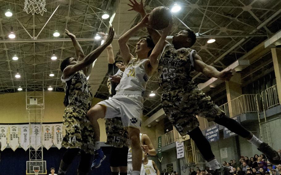 Yokota's Hunter Cort is met by Humphreys' defenders Malik Dampier (left), Bashr Edmonds (right) and Omar Lopez while driving down the baseline during the Far East Tournament Boys Division II championship game Feb. 18, 2016 at Yokota Air Base, Japan. Yokota defeated Humphreys 67-51 to repeat as champions. 