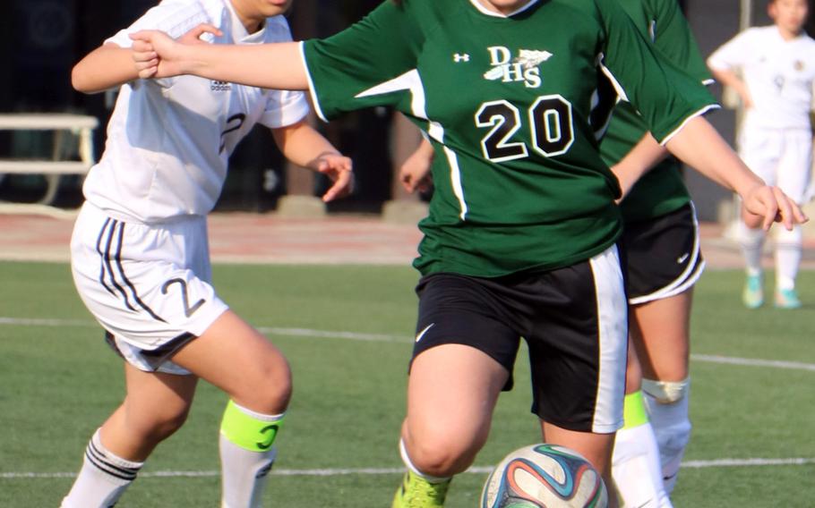 Daegu's Sadie Giles dribbles away from the Taejon Christian defense during Wednesday's girls soccer match. The Dragons blanked the Warriors 3-0.