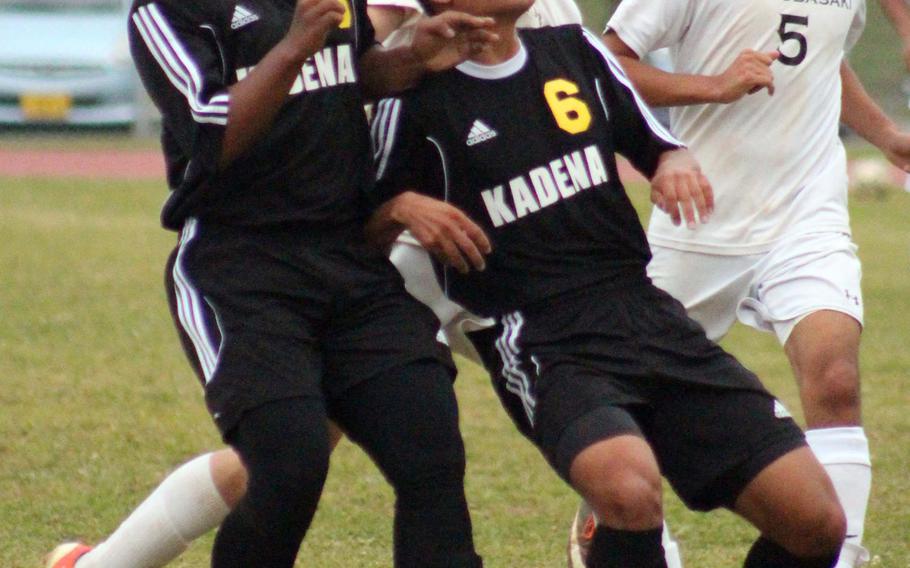 Kadena's Quentin Moore heads the ball next to teammate Bryan Vaden as Kubasaki's Christian Macaluso watches in the distance during Wednesday's boys soccer match, won by the Dragons 2-0.