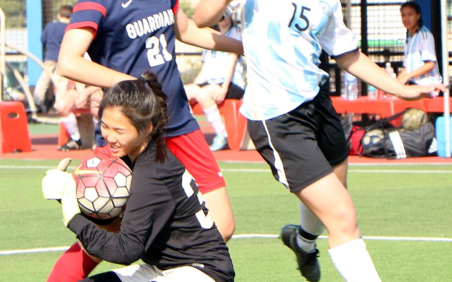 Yongsan International-Seoul keeper Asia Yi grabs the ball as teammate Jane Warren, left, and Osan's Elizabeth White run past her during the Korea Blue tournament semifinal on Friday, April 29, 2016. Osan won, 2-1.



