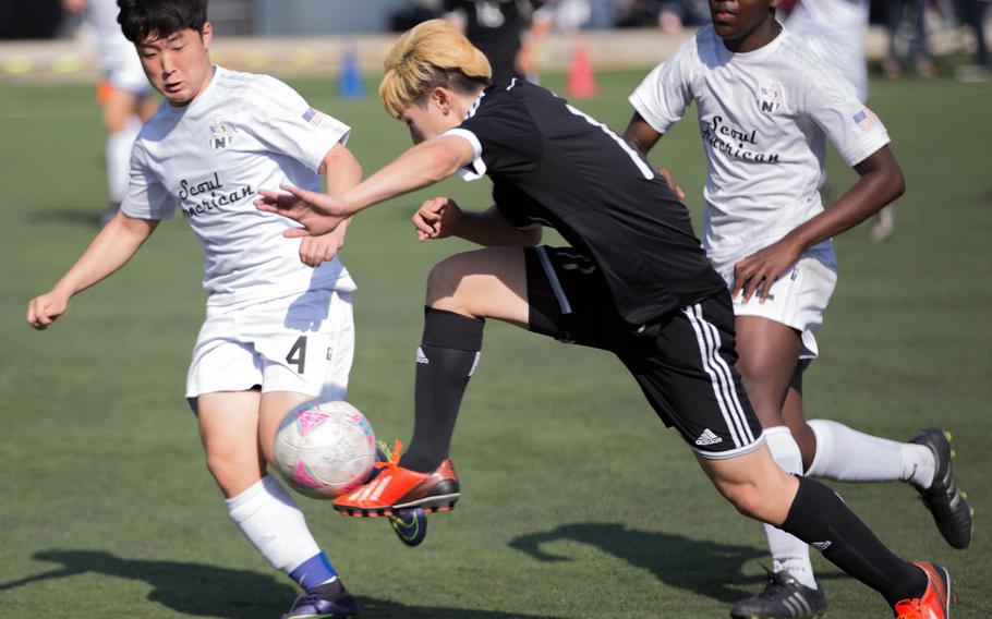Taejon Christian's Gil Jang takes off with the ball between Seoul American's Kevin Hwang and Kevin McGuire during Friday's Korea Blue tournament semifinal. The Dragons won in a penalty-kick shootout.