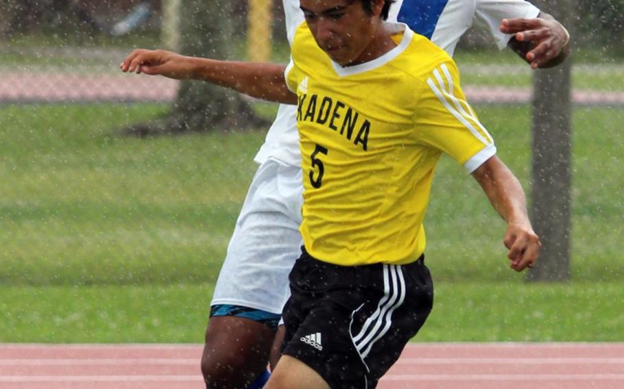 Christian Academy Japan's Lawrence Yamaguchi and Kadena's Eric Fletcher chase the ball during Monday's Far East Division I Boys Soccer Tournament pool-play match. The teams battled in the rain to a 2-2 draw.