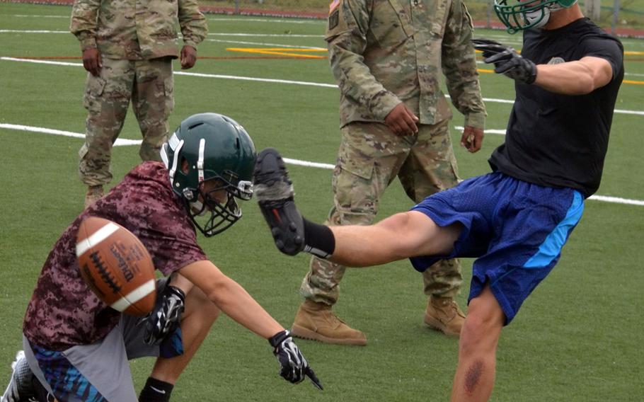 Daegu senior Tommy Kazmierczak tries his hand at placekicking under the watchful eye of assistant coaches.