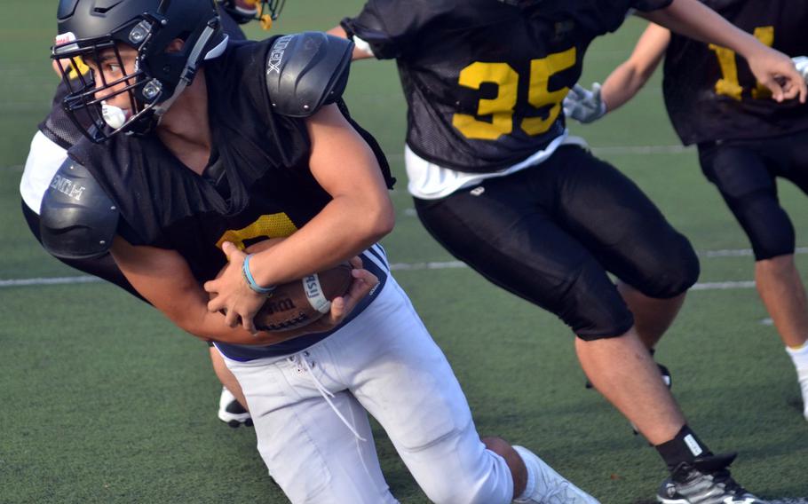 Jake Noddin carries the ball as veteran ASIJ lineman Dalan Gerber draws a bead on him in practice.