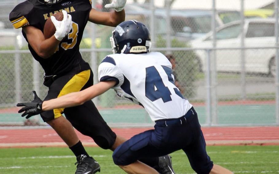 Kadena wide receiver Donte Savoy looks for running room against Seoul American linebacker Sean Sullivan.