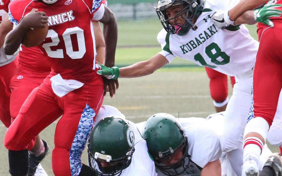 Nile C. Kinnick running back Chauncey Jamerson gets wrapped up by two Kubasaki linemen as the Dragons' Alex Ramos also gives chase. Kubasaki won 13-6.