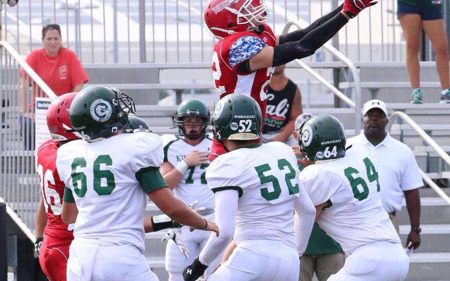 Nile C. Kinnick receiver Josh Brotherton goes airborne for a pass over a circle of teammates and Kubasaki Dragons defenders. Kubasaki won 13-6.