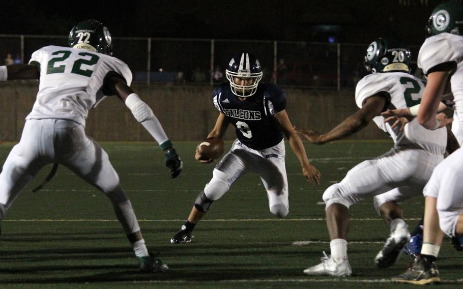 Seoul American quarterback David Messinger looks for room to avoid the tackle of Kubasaki's Trey McKoy, Antonio Mitchell and Hayden Williamson.