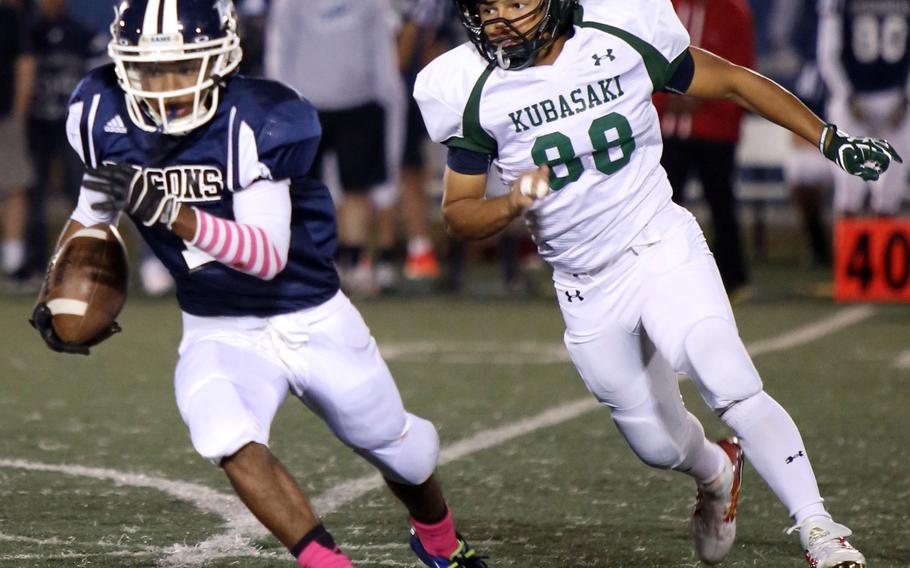 Seoul American running back M.J. Haynes runs to avoid the tackle of Kubasaki defensive back Omar Garcia.