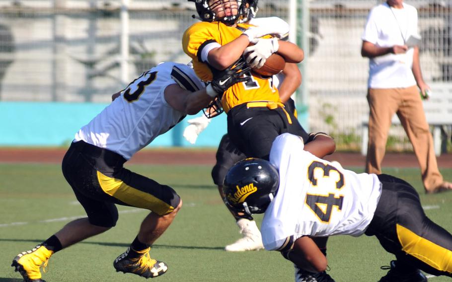 American School In Japan running back Andrew Howe gets sandwiched by Kadena defenders Ahmad Carter and Uriah Morris.