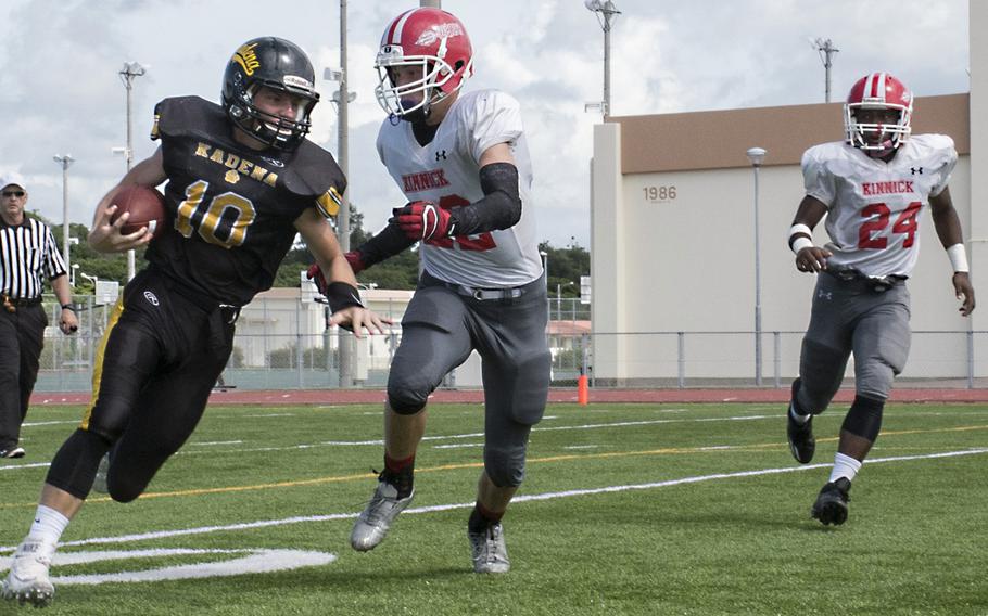 Kadena quarterback Cody Sego runs around right end against Nile C. Kinnick defenders Josh Brotherton and Dwayne Lyon.